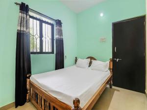 a bedroom with a bed with a black door and a window at OYO Hotel 49339 On The Rocks in Arambol