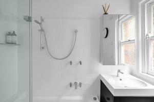 een witte badkamer met een douche en een wastafel bij 'Beachside Bliss' Heart of the Coastal Lifestyle in Sydney