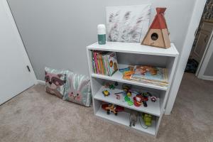 un estante de libros blanco con juguetes y una casa de aves en 3 Bedroom Haven of Rest-5 Minutes from Mayo Clinic!, en Rochester