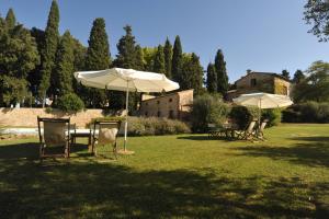 einen Tisch und Stühle mit Sonnenschirmen auf einem Feld in der Unterkunft Fattoria Lornano Winery in Monteriggioni