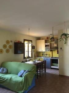 a living room with a green couch and a kitchen at Il mondo magico - Immerso nella natura - in Fauglia