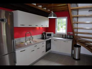 a kitchen with white cabinets and a red wall at Le Pressoir de Bigard - chaumière normande - 8 personnes in Campigny +24 photos