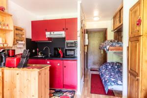 a small kitchen with red cabinets and a bunk bed at Le Petit Aulps - Studio avec vue montagne in Saint-Jean-d'Aulps