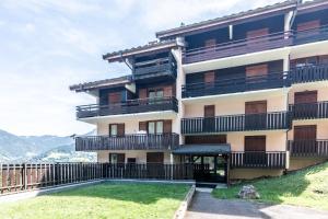 a large building with balconies and a yard at Le Petit Aulps - Studio avec vue montagne in Saint-Jean-d'Aulps