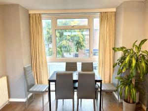 a dining room with a table and chairs and a window at Beautiful 3-bed apartment at Swiss Cottage in London