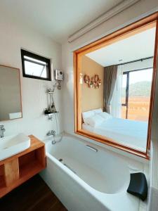 uma casa de banho com uma banheira, uma cama e uma janela em Chacha Tyme Pool Villa Khaoyai em Wangkata