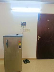 a refrigerator in a room next to a wooden door at Pretty Garden View Apartment 3BHK Furnished Flat near Kashi Vishwanath Temple in Varanasi