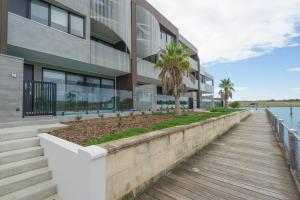 un bâtiment avec une passerelle en bois à côté de l'eau dans l'établissement Waterfront at Martha Cove - Premium Poolside Luxury, à Safety Beach