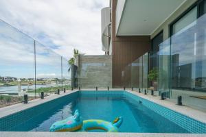 a swimming pool with two inflatable dolphins in front of a house at Waterfront at Martha Cove - Premium Poolside Luxury in Safety Beach