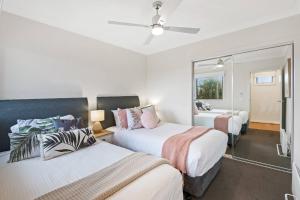 ローズバッドにある'Rosebud Seascape' A Modern Family Retreatのベッド2台と鏡が備わるホテルルームです。
