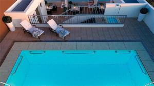 a blue swimming pool with two chairs and a table at Edificio Bulnes Iquique in Iquique