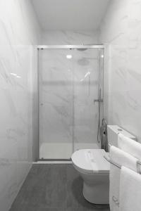 a white bathroom with a shower and a toilet at Via Augusta 129 in Lisbon