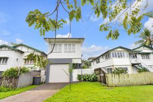 Biały dom z ogrodzeniem i ogródkiem w obiekcie Modern meets Tropical in this Free-standing Home w mieście Cairns North