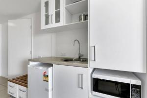 Una cocina blanca con fregadero y microondas. en Coastal Chic in Heart of Cairns with Rooftop Pool, en Cairns