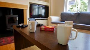 a living room with a coffee table with two mugs on it at Fire Station Cottage in Comrie