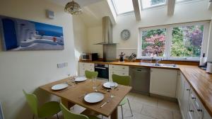 a kitchen with a wooden table and green chairs at Fire Station Cottage in Comrie