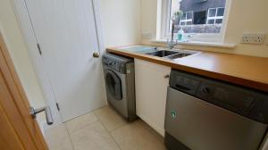 a kitchen with a sink and a washing machine at Fire Station Cottage in Comrie