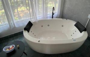 uma grande banheira branca na casa de banho com uma janela em Rancho do Zé João em Lavrinhas