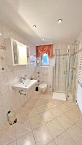 a bathroom with a sink and a shower and a toilet at Villa Vivien Wohnung Hühnergott in Göhren