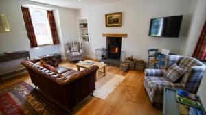 a living room with a couch and chairs and a fireplace at Edinample Lodge in Lochearnhead