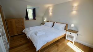 a bedroom with a large white bed and a wooden floor at Edinample Lodge in Lochearnhead +17 photos