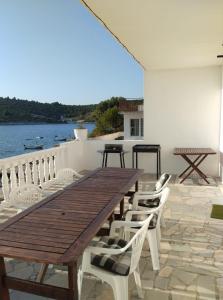 einen Holztisch und Stühle auf einer Terrasse mit Wasser in der Unterkunft Kanica seaside apartment Roko 10 m from sea in Sevid