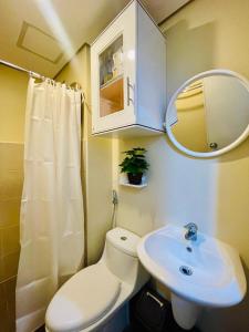 a bathroom with a toilet and a sink and a mirror at City View Studio Unit at Centrio Tower beside Ayala Mall in Cagayan de Oro