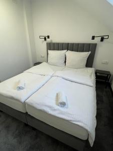 a large bed with white sheets and towels on it at Hotelik Maria in Szczytno