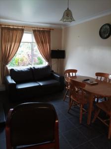 sala de estar con sofá negro y mesa en Teach pádraig en Falcarragh