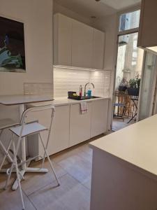 uma cozinha com armários brancos e uma mesa e cadeiras em Haussmannien lumineux em Marselha