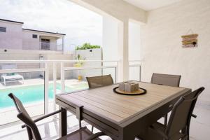 - Balcón con mesa de comedor y sillas y piscina en Villa des Pentas – Chaleureuse Villa moderne avec piscine, en Baie-Mahault