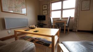 a living room with a coffee table and a couch at Morenish Mews Killin Cottage in Morenish