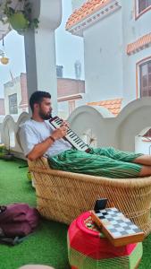 a man playing a accordion on a patio at Manavi Home Stay in Mathura