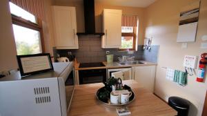 Morenish Mews Kenmore Cottage في Morenish: مطبخ مع طاولة عليها صحن