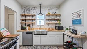 a kitchen with white cabinets and a sink and a window at Curated Cottage. minutes from Silos, zoo, Baylor in Waco