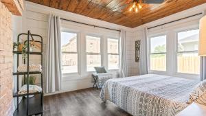 a bedroom with a bed and two windows at Curated Cottage. minutes from Silos, zoo, Baylor in Waco