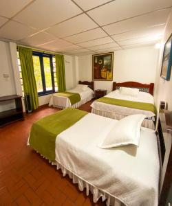 a hotel room with two beds with green curtains at Ecohotel La Casona Pereira in Pereira