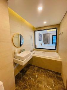 ein Badezimmer mit einem Waschbecken, einem Spiegel und einer Badewanne in der Unterkunft FLC Apartment Beach Quy Nhơn in Quy Nhon