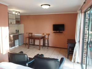 a living room with a table and chairs and a tv at Kwena Maribane Lodge in Bronkhorstspruit