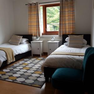 1 dormitorio con 2 camas, ventana y alfombra en Beech House, en Fort William