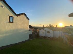 ein Haus, in dem die Sonne hinter einem Zaun untergeht in der Unterkunft Forest Hill View in Cinderford