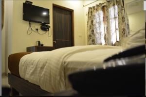 HOTEL AVISHA Residency في Marmagao: غرفة نوم مع سرير وتلفزيون على الحائط