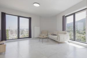 a white living room with large windows and a couch at Green Eyes Apartments in Sofia