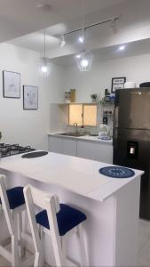 a kitchen with a white counter with two blue chairs at Greece In Home in Girardot