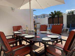 a wooden table with chairs and an umbrella on a patio at Villa Rosa in Costa Teguise