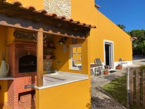 Una casa amarilla con un horno de pizza al costado. en Countryside & Beach House Ericeira - Pêra Miúda, en Ericeira