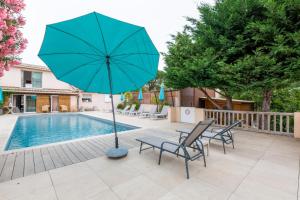 un patio con sillas y una sombrilla junto a la piscina en Chambres d'Hotes Les Amandiers, en Saint-Tropez