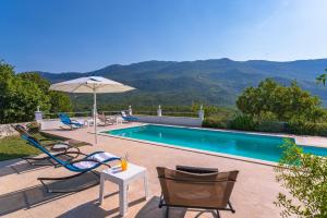 a swimming pool with chairs and a table and an umbrella at Villa Luce in Omiš