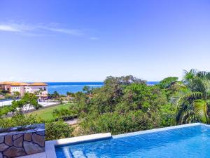ein Swimmingpool mit Blick auf das Meer in der Unterkunft Pristine Bay 1106 home in Roatán
