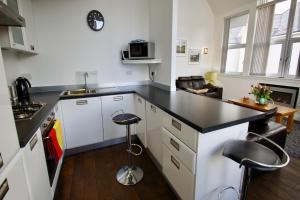 a kitchen with white cabinets and a black counter top at Penthouse Apartment in Stirling